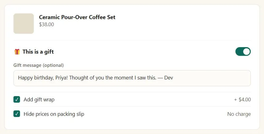 A checkout line item for a "Ceramic Pour-Over Coffee Set" with a "This is a gift" toggle switched on, a filled-in gift message reading "Happy birthday, Priya! Thought of you the moment I saw this. — Dev," and two checked options below it: "Add gift wrap" (+$4.00) and "Hide prices on packing slip" (no charge)